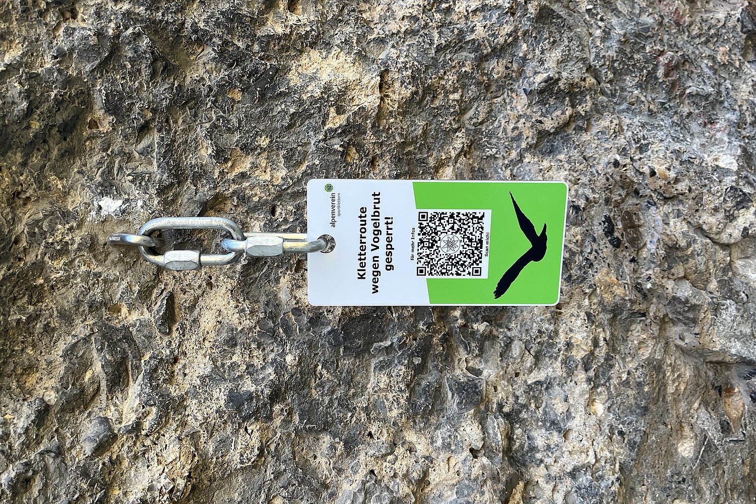 Sperrtafel an einer Kletterwand, die per QR-Code über die in der Felswand brütende Vogelart informiert.