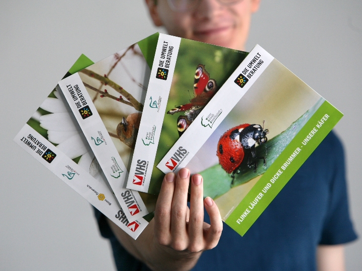 Person, die vier zusammengefaltete Tierposter in der Hand hält.